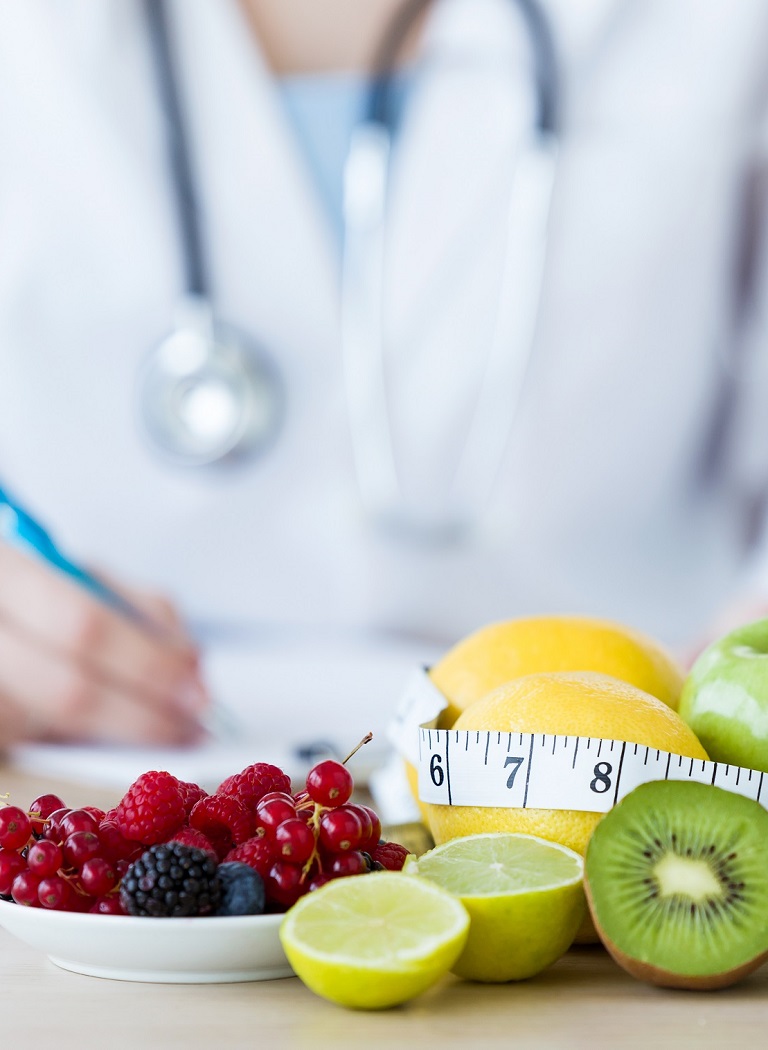 Close-up of some fruits such as apples, kiwis, lemons and berries on nutritionist table.
